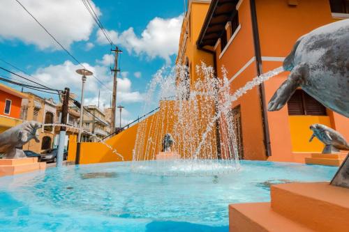 a fountain with dolphin statues in front of a building at Atenas City Inn in Manati