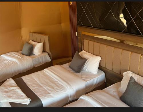two beds in a room with white sheets and pillows at The bubble camp in Aqaba