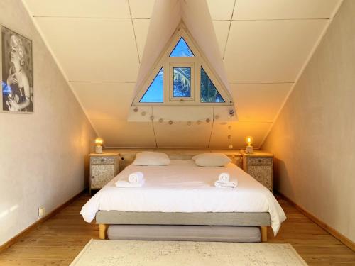 een zolderkamer met een bed met een raam bij Villa Blue Waves in Saint-Gilles-les-Bains