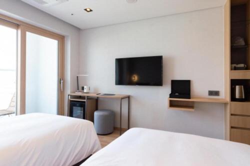 a bedroom with a bed and a tv on the wall at Connect Busan Hotel & Residence in Busan