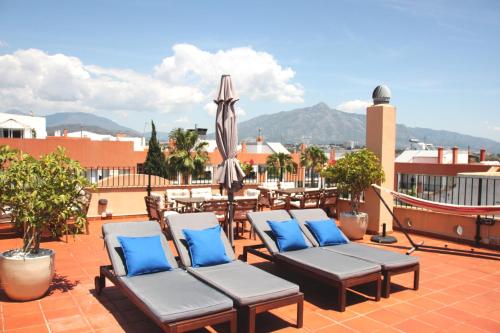 馬貝拉的住宿－卡塔莉娜夫人酒店，庭院配有椅子和遮阳伞及桌子。