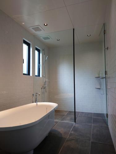 a bathroom with a tub and a glass shower at VILLA Esse UNA in Nago