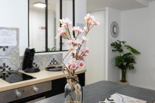 a vase filled with pink flowers on a table at Le nid douillet - Centre Ville - 3 étoiles in Bourg-en-Bresse