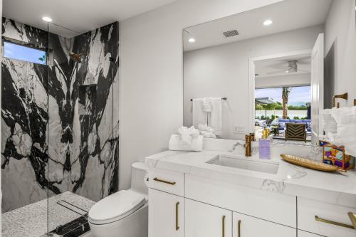 a bathroom with a sink and a toilet and a mirror at Lazy River Oasis in Bermuda Dunes