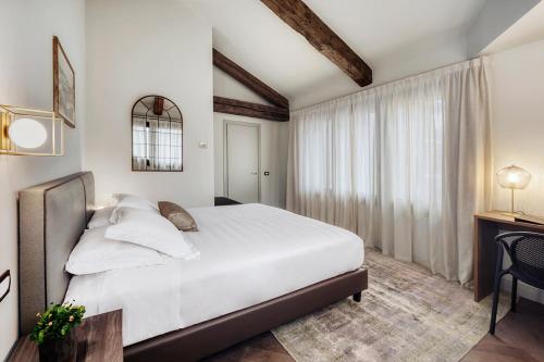 una camera da letto con un grande letto bianco e una finestra di Hotel Carlton a Treviso