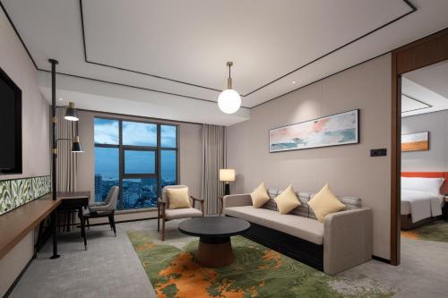 a living room with a couch and a bed at Hilton Garden Inn Beihai Jiafu in Beihai