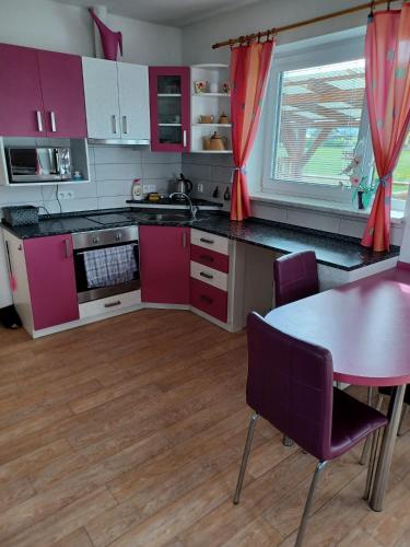 a kitchen with pink cabinets and a table with chairs at Apartmány Kojčice 