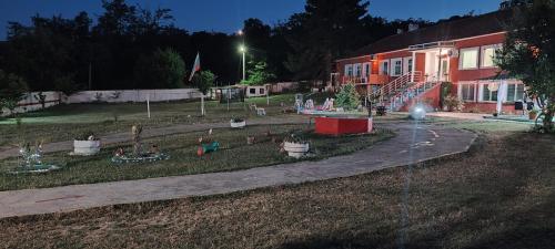 a park with a playground with potted plants at night at Къща за гости сБолярци 