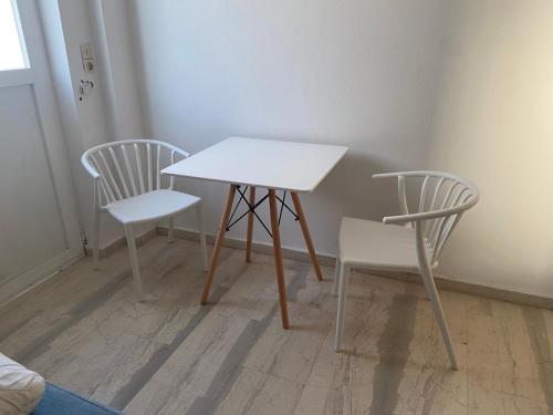 a white table and two chairs in a room at PAGONI apartments in Kardamaina