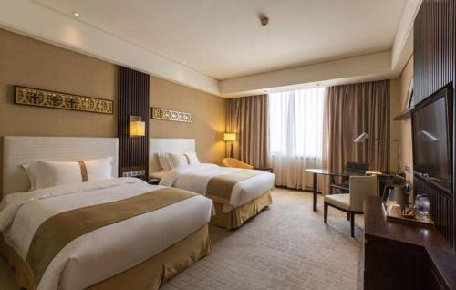 a hotel room with two beds and a flat screen tv at Datong Hotel in Datong