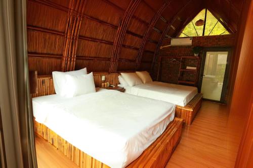 two beds in a room with a window at Woodstock Jungle Camp in Cat Ba