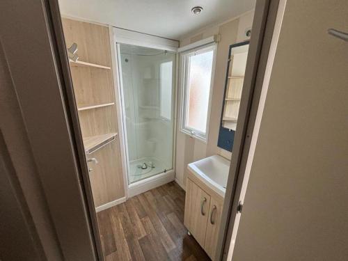 une salle de bain avec une douche, un lavabo et un miroir dans l'établissement Mobil home - Rieumontagne Particulier, à Nages