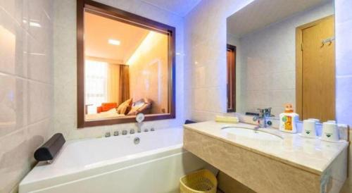 a bathroom with a sink and a mirror and a tub at GreenTree Inn Nantong University Industrial Expo City Express Hotel in Nantong