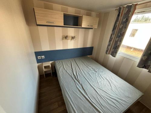 une petite pièce avec un lit et une fenêtre dans l'établissement Mobil home - Rieumontagne Particulier, à Nages