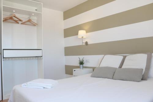 1 dormitorio con cama blanca y pared a rayas en Apartment Sky Cervantes, en Málaga