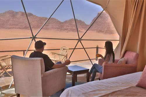 a man and woman sitting in chairs looking out at the desert at The bubble camp in Aqaba