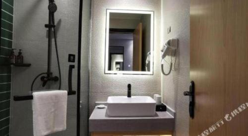 a bathroom with a white sink and a mirror at GreenTree Inn Ganzhou Gan County Bus Station in Ganzhou