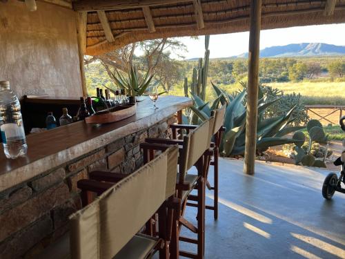 a bar with chairs and a view of the desert at Hohewarte Guestfarm in Windhoek