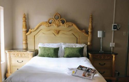 a bedroom with a white bed with a wooden headboard at 54 River Logde in Mokopane