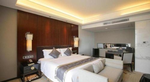a bedroom with a large white bed and a desk at Zhangjiagang Zhonglian GDH International Hotel in Zhangjiagang
