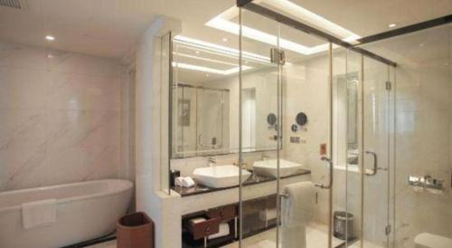 a bathroom with a tub and a sink and a shower at Zhangjiagang Zhonglian GDH International Hotel in Zhangjiagang
