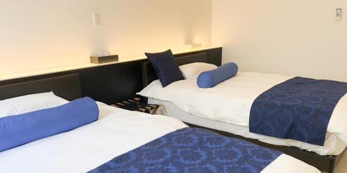 two beds in a room with blue and white at ブルーシャローズ 恩納村リゾート in Ukaji