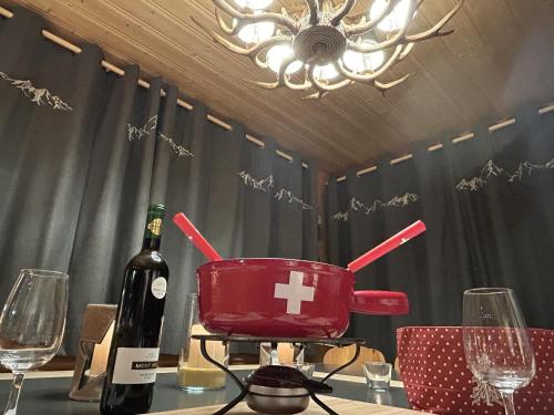a bottle of wine and a pot on a table with wine glasses at Le Pacheu in Les Crosets