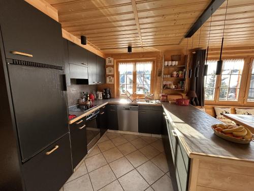 a kitchen with black appliances and a wooden ceiling at Le Pacheu in Les Crosets