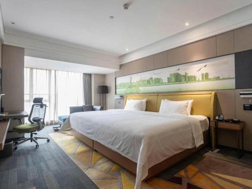 a hotel room with a large bed and a desk at Hampton by Hilton Zhuhai Doumen in Zhuhai