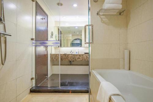 um banheiro com chuveiro, banheira e pia em Qingdao Blue Horizon Hotel Laoshan em Qingdao