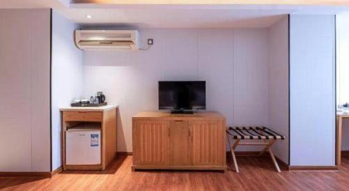 a room with a tv on a wooden stand with a bench at Zhongshan Louis Hotel in Zhongshan