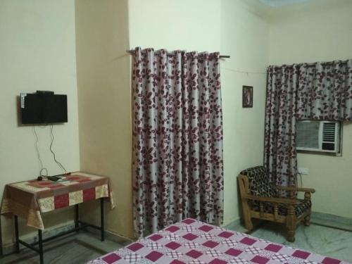a room with a bed and a chair and curtains at Virat Home in Gwalior