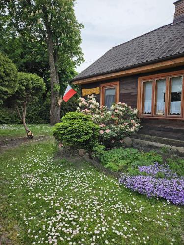 a house with a garden of flowers in front of it at Niemirowska Osada in Niemirów