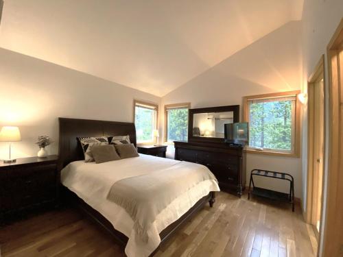 a bedroom with a bed and a tv and windows at Echo Hills Mountain Lodge - Evergreen Mountain Top Retreat - 15 minutes to SKI!! in Evergreen
