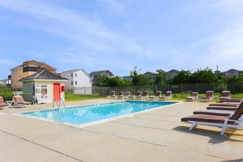 a swimming pool with chaise lounge chairs and a swimming pool at SDV309 - Chiller Whale: 1 Block to Beach in Kill Devil Hills