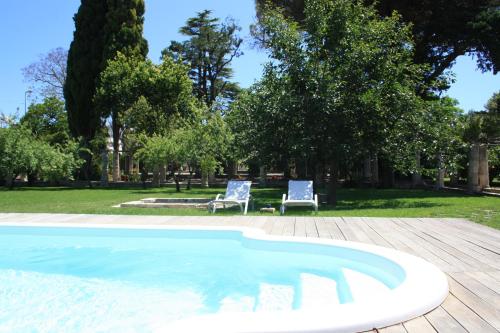 a swimming pool with two chairs and trees at Castello di Casamassella - Marea Stays Collection in Casamassella
