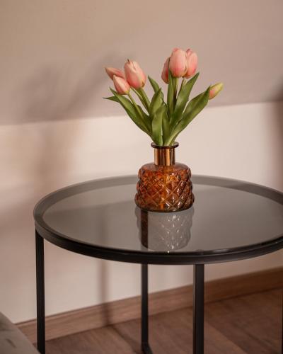 a glass table with a vase with pink flowers on it at Glamping Gozdna Jasa in Bovec