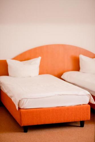 an orange bed with two pillows on top of it at Stube Hotel und Gasthaus in Nordrach