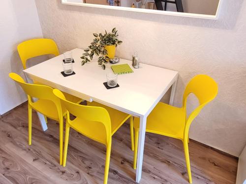 a table and chairs with a white table and yellow chairs at Mien lüttes Glück -Fewo Backboord in Zempin