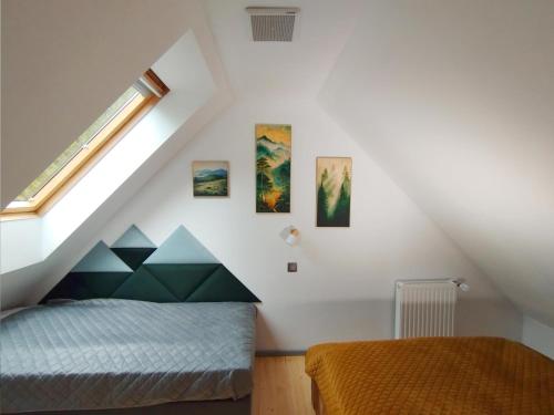 a attic bedroom with a bed and a window at Apartament Górska Przystań - Willa Marysin in Bukowina Tatrzańska