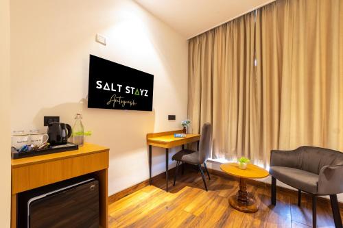 a hotel room with a sitting area and a tv at Saltstayz Autograph - Advant & Sector 144 in Noida