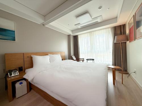 a bedroom with a large white bed and a window at Sokcho Marina Hotel in Sokcho