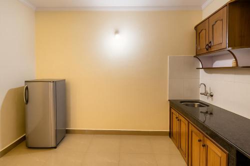 a kitchen with a stainless steel refrigerator and wooden cabinets at Sonikas Holiday Homes (Studio) in Candolim