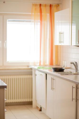 a kitchen with white cabinets and a sink and a window at Stube Hotel und Gasthaus in Nordrach