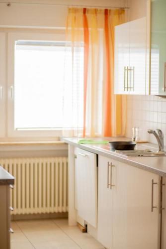 a kitchen with white cabinets and a window and a sink at Stube Hotel und Gasthaus in Nordrach