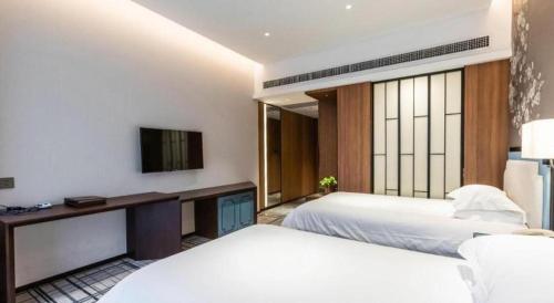 a hotel room with two beds and a television at International Conference Hotel Nanjing in Nanjing