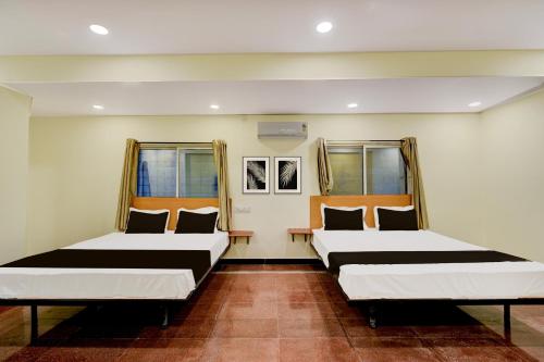 two beds in a room with two windows at Hotel O SVR Grand Inn in Surūrnagar