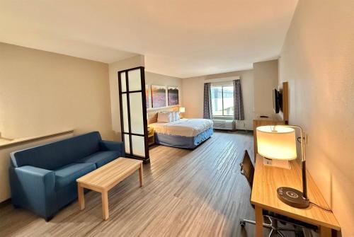 - un salon avec un canapé bleu et un lit dans l'établissement Days Inn & Suites by Wyndham Houston / West Energy Corridor, à Houston