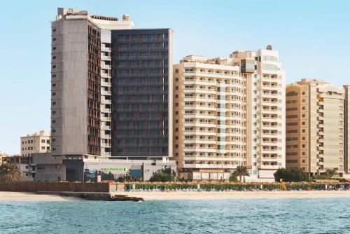 a group of tall buildings next to a beach at Wyndham Garden Ajman Corniche in Ajman 