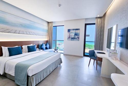 a hotel room with a large bed with blue pillows at Wyndham Garden Ajman Corniche in Ajman 